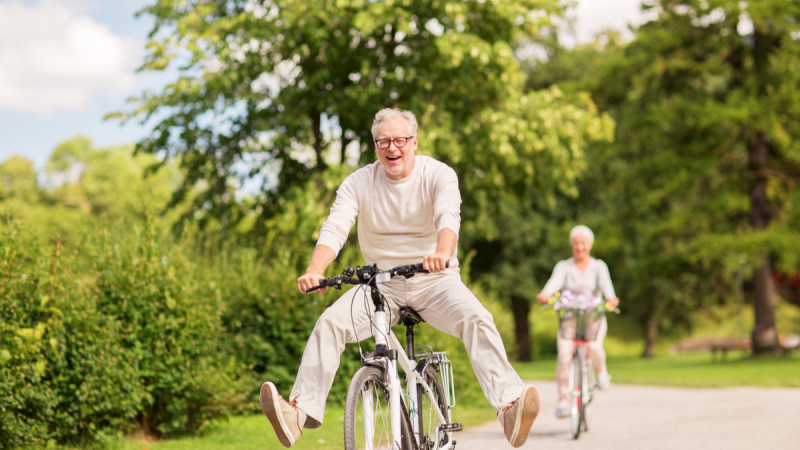 Older man and woman wearing white are riding bicycles