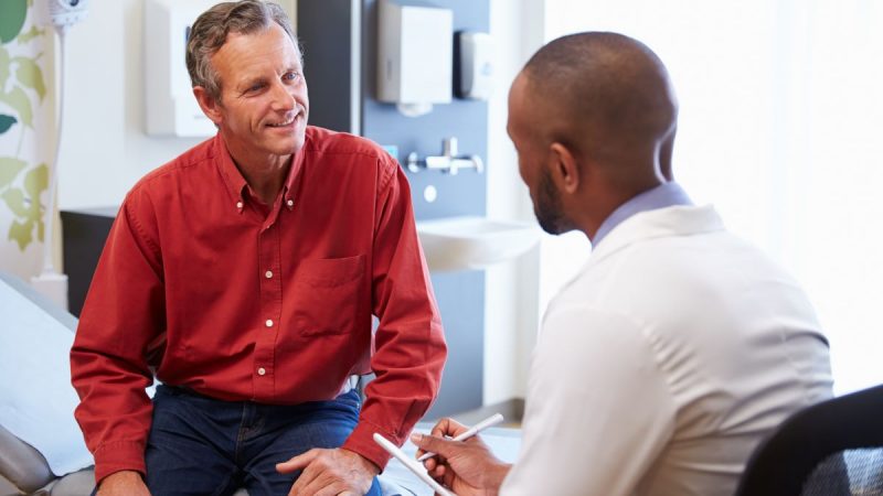 Male patient in red shirt speaks with doctor